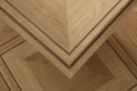 Close-up of a wooden furniture corner showing layered wood veneer panels with a geometric chevron pattern and contrasting dark inlay lines.