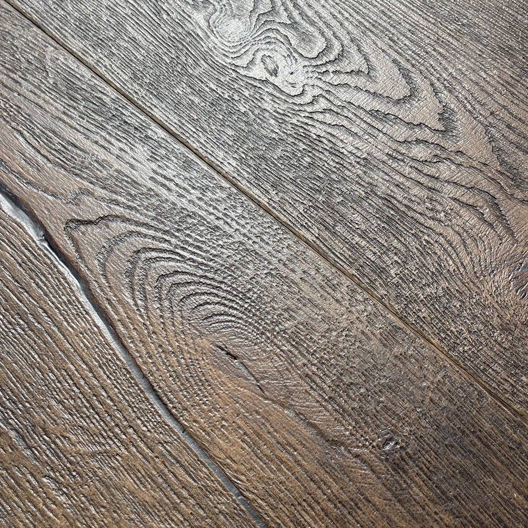 Close-up of rustic wood flooring planks with a weathered brown and gray finish, showing detailed grain patterns and natural wood textures.