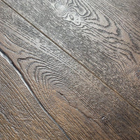 Close-up of rustic wood flooring planks with a weathered brown and gray finish, showing detailed grain patterns and natural wood textures.