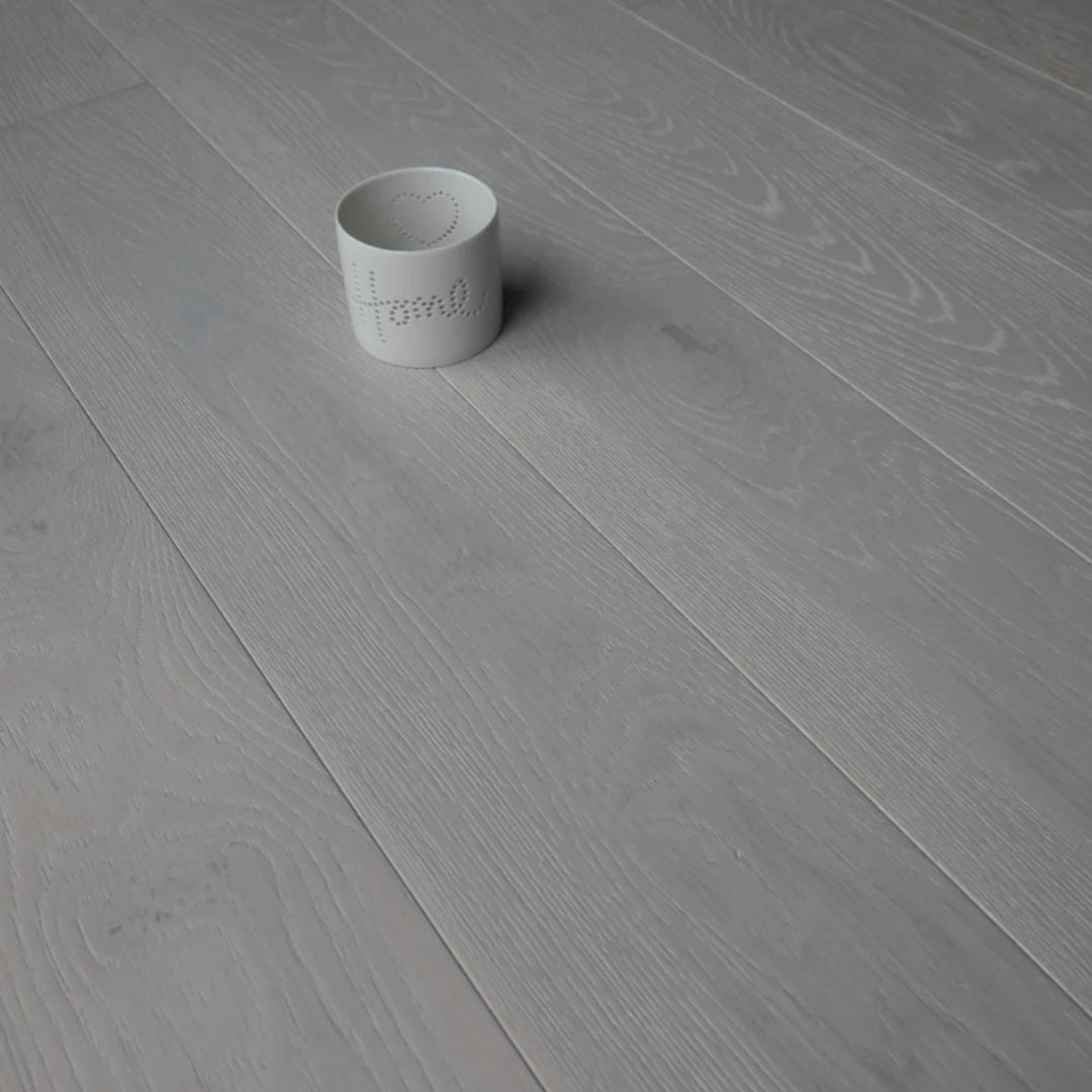 Light gray wood-look flooring planks with a small white ceramic cup placed on top.
