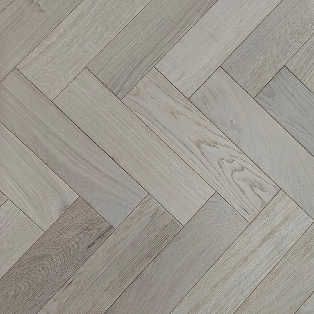 Light oak herringbone parquet flooring with a natural wood grain finish.
