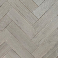 Light gray wood-look flooring planks arranged in a herringbone pattern, showing natural grain texture.