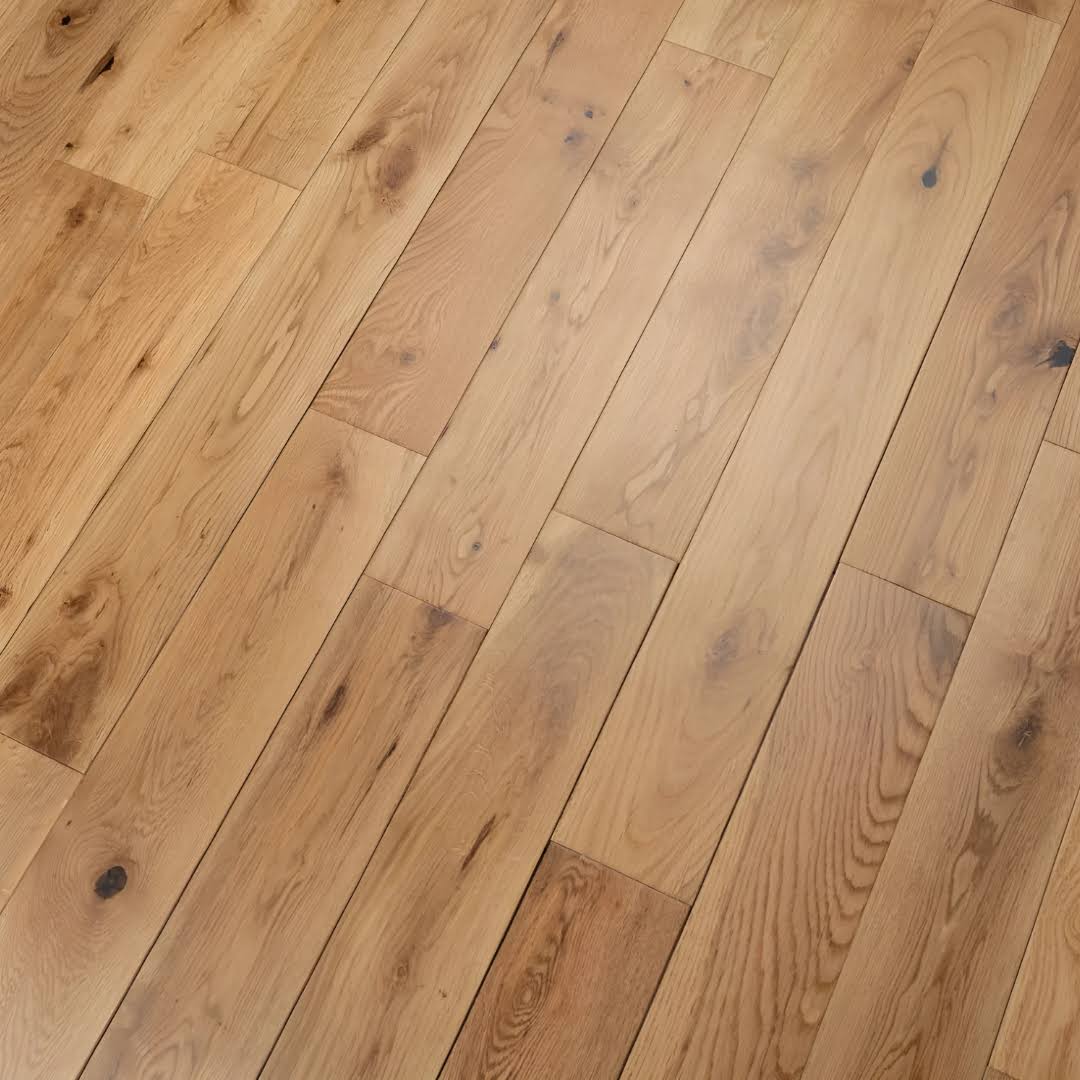 Light natural wood flooring planks arranged in a herringbone pattern, showing warm tan and brown tones with visible wood grain and knots.